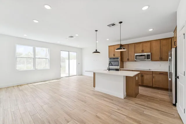 a kitchen with stainless steel appliances granite countertop a sink a stove a refrigerator cabinets and wooden floor