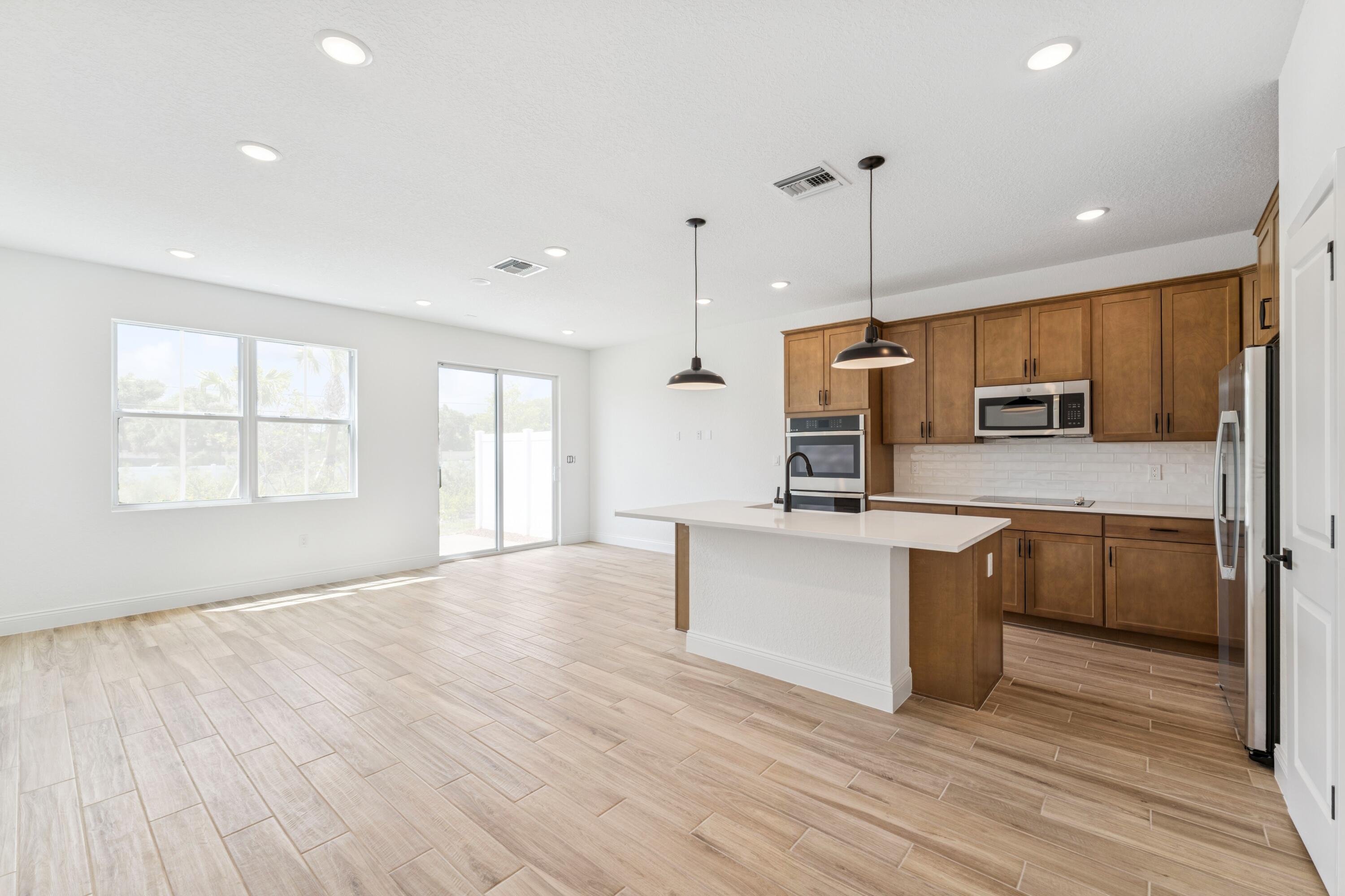 164 Southeast Birch Terrace, Unit 103 Stuart, FL 34997 - Photo 6 of 29 a kitchen with stainless steel appliances granite countertop a sink a stove a refrigerator cabinets and wooden floor