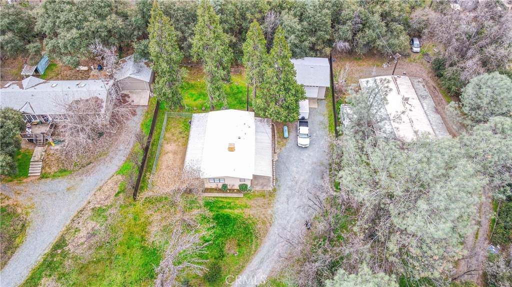 aerial view of a house with a yard and trees all around
