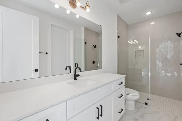 a bathroom with a toilet sink vanity and mirror