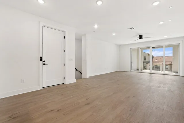 an empty room with windows and ceiling fan