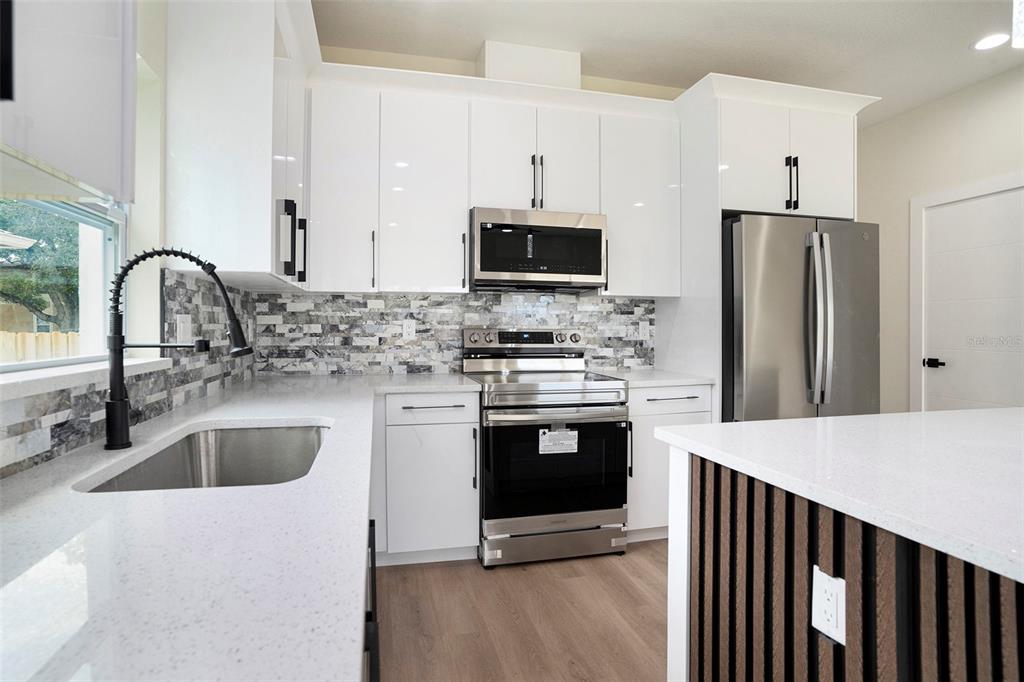 3612 Temple Street Tampa, FL 33619 - Photo 12 of 26 a kitchen with stainless steel appliances granite countertop a sink stove and refrigerator