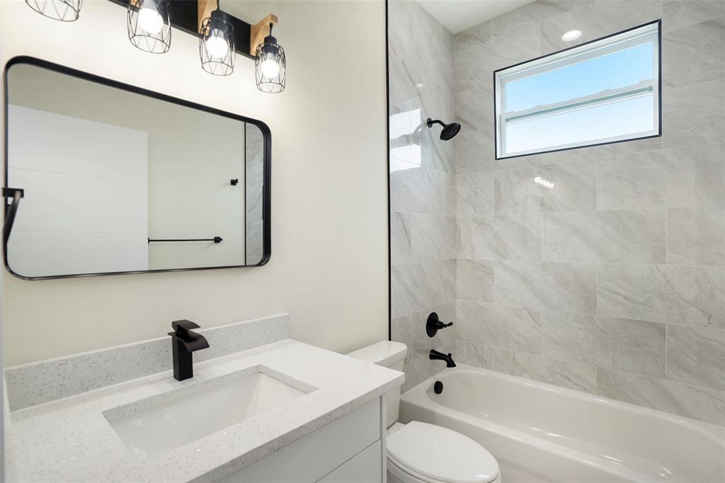 3612 Temple Street Tampa, FL 33619 - Photo 23 of 26 a bathroom with a granite countertop sink a toilet and a bathtub