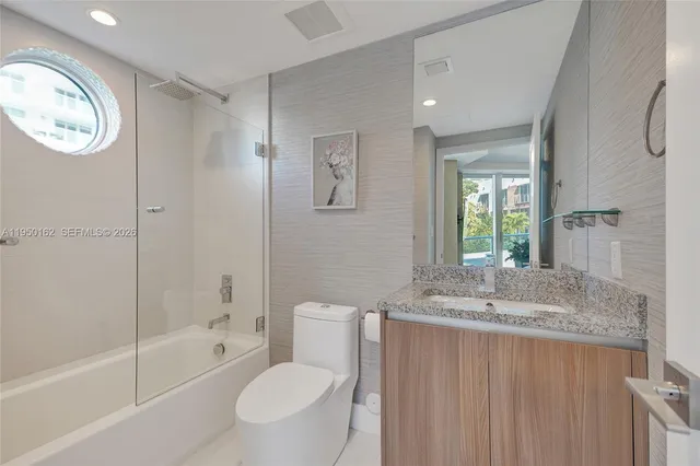 a bathroom with a granite countertop sink mirror vanity and toilet