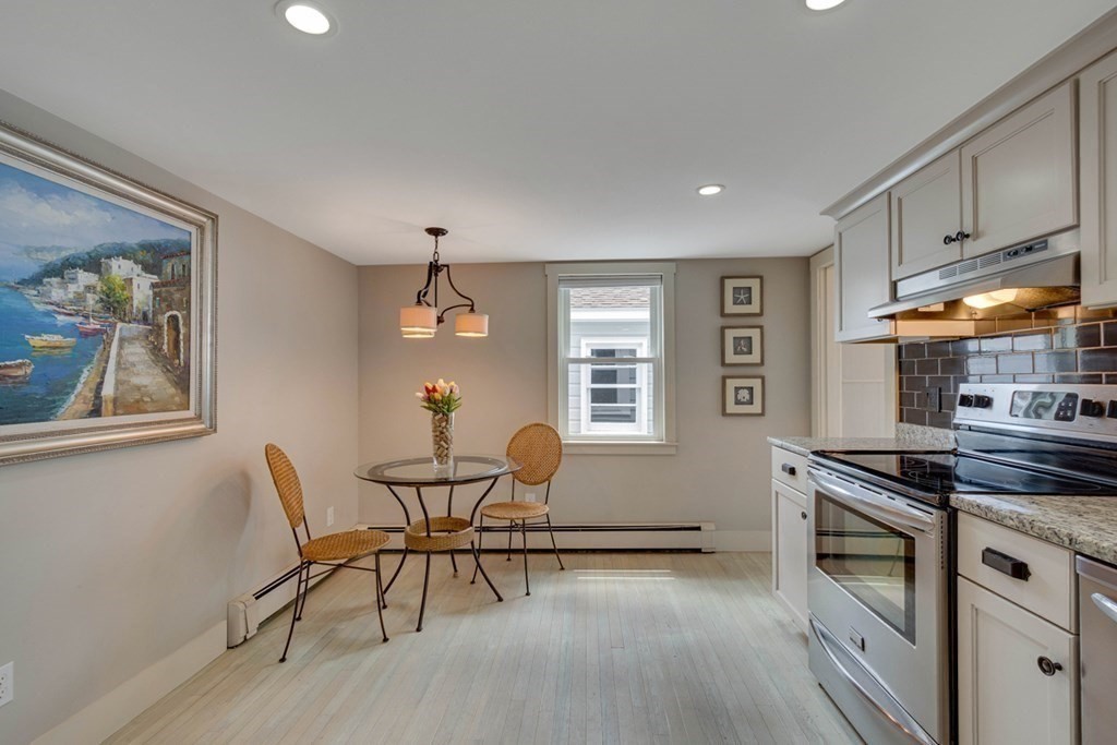 16 Milford Avenue Natick, MA 01760 - Photo 14 of 34 a kitchen with stainless steel appliances granite countertop a stove top oven a dining table and chairs with wooden floor