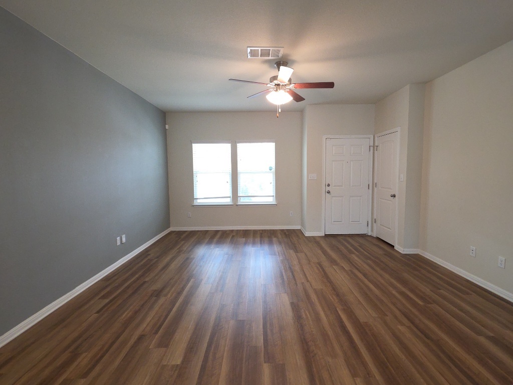 18009 Malnati Drive Pflugerville, TX 78660 - Photo 2 of 22 a view of an empty room with wooden floor and a window