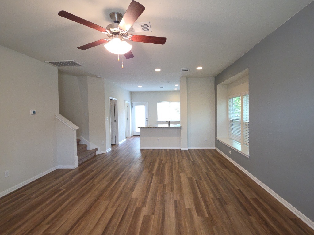18009 Malnati Drive Pflugerville, TX 78660 - Photo 3 of 22 a view of an empty room with window and wooden floor