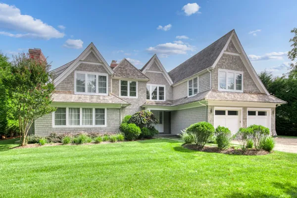 a front view of a house with a yard and potted plants