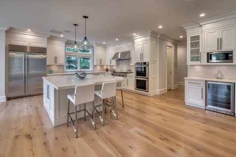 a kitchen with stainless steel appliances a dining table chairs stove refrigerator and cabinets