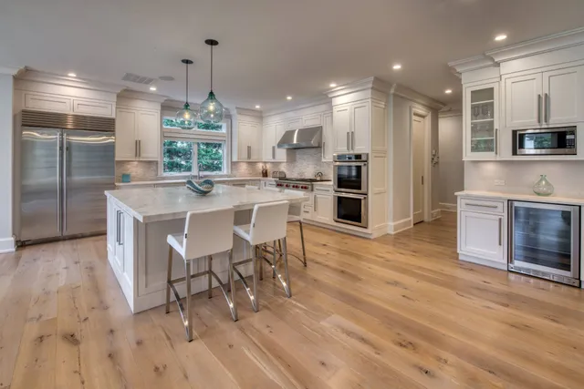 a kitchen with stainless steel appliances a dining table chairs stove refrigerator and cabinets