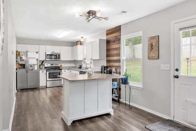 a kitchen with stainless steel appliances a sink a stove a refrigerator cabinets and a window