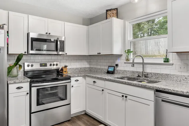 a kitchen with granite countertop white cabinets white stainless steel appliances and a sink