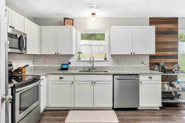 a kitchen with granite countertop white cabinets and white appliances