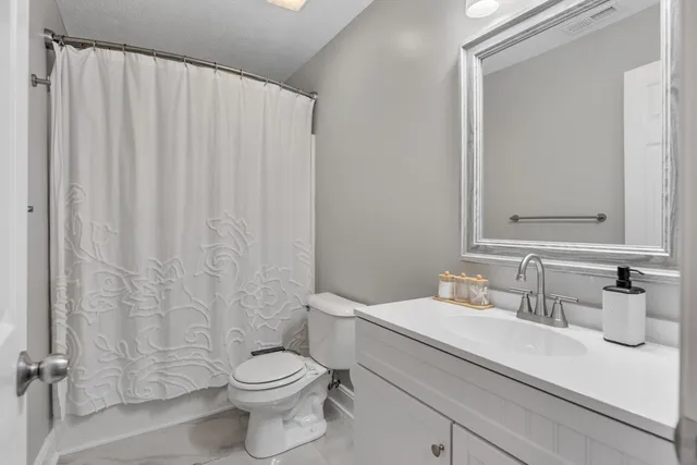 a bathroom with a sink a toilet and shower curtain