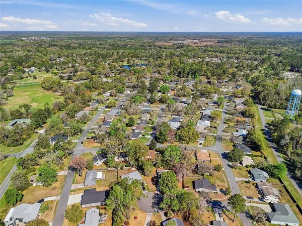 an aerial view of residential houses with outdoor space and trees