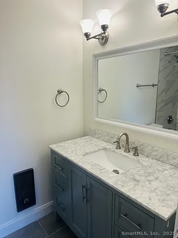 a bathroom with a granite countertop sink a mirror and shower