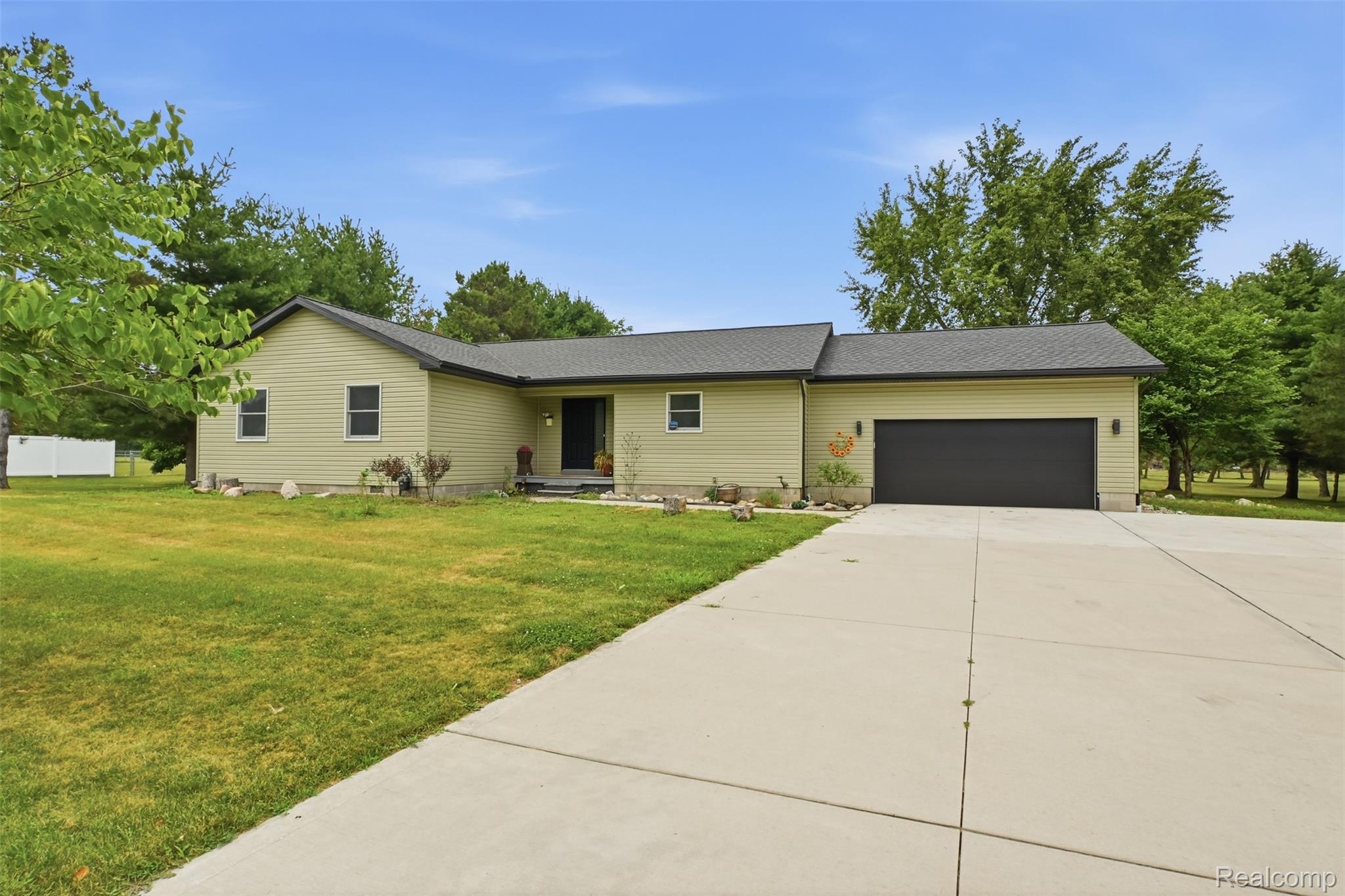 45738 Bemis Road Belleville, MI 48111 - Photo 1 of 52 Ranch-style residence featuring light-toned siding, a dark roof, and an attached two-car garage with a dark door