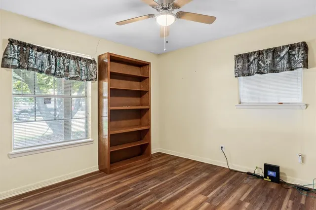 wooden floor in an empty room with a chandelier fan