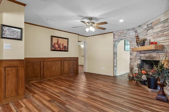 an empty room with wooden floor chandelier fan and windows