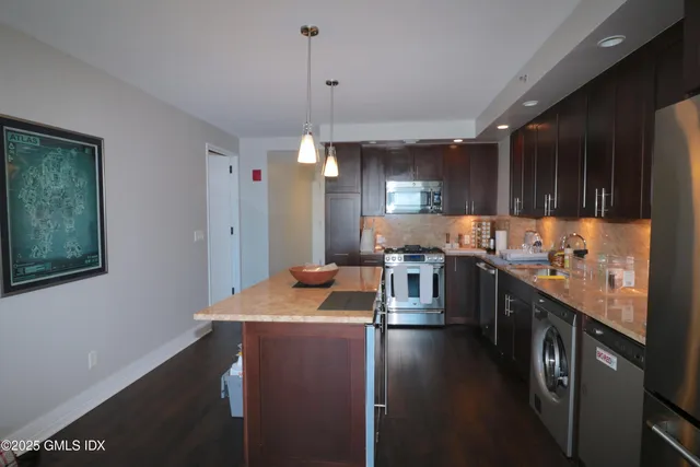 a kitchen with stainless steel appliances granite countertop a sink a stove and a refrigerator