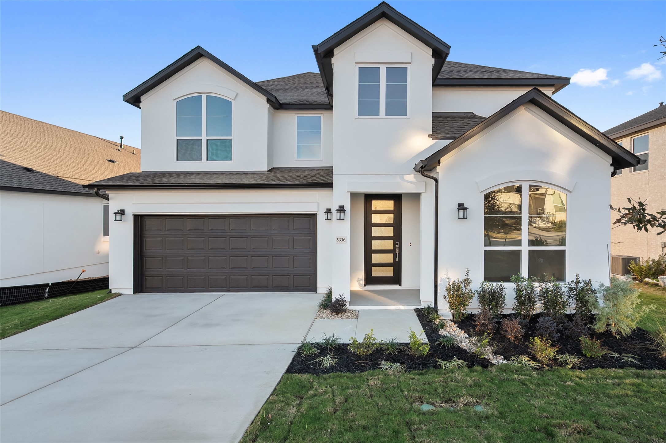 View of front of home with stucco siding, a garage, driveway, and a shingled roof