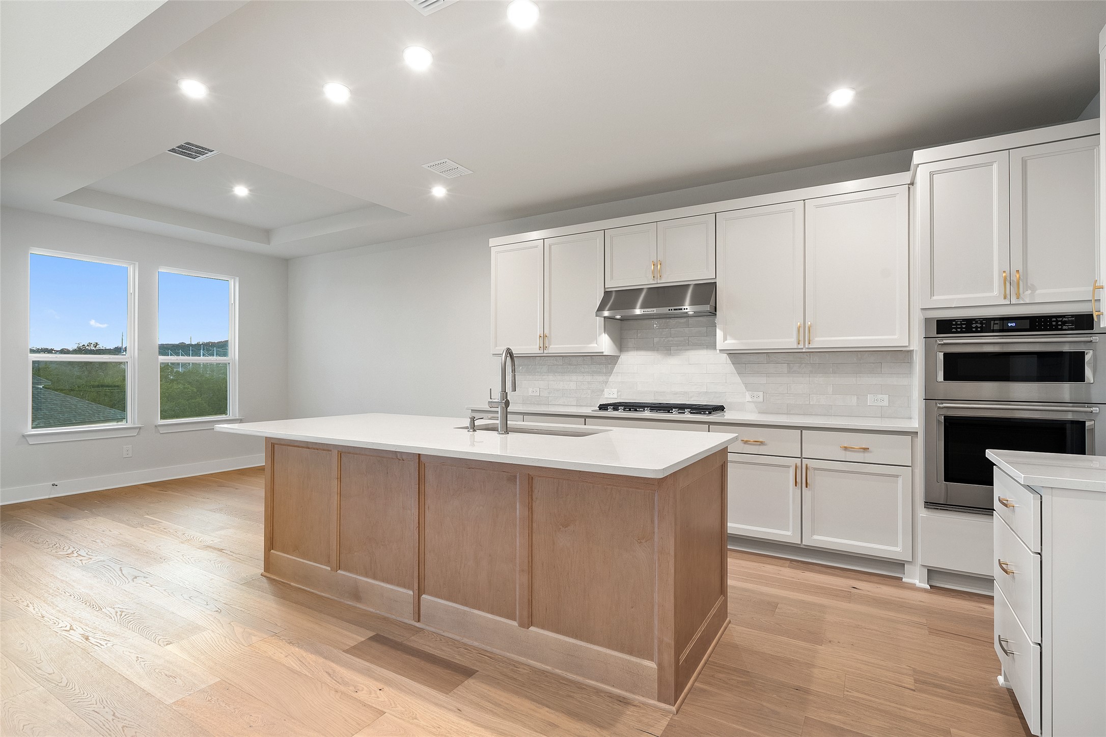 5336 Cosenza Trace Leander, TX 78641 - Photo 12 of 40 Kitchen with double oven, white cabinetry, recessed lighting, backsplash, and under cabinet range hood
