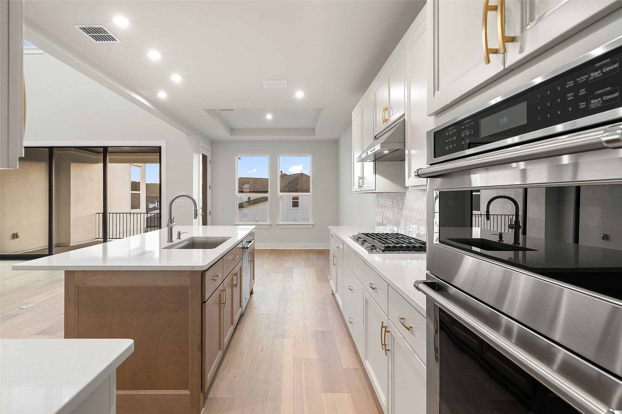 5336 Cosenza Trace Leander, TX 78641 - Photo 16 of 40 Kitchen with appliances with stainless steel finishes, white cabinets, recessed lighting, a raised ceiling, and light wood-style flooring