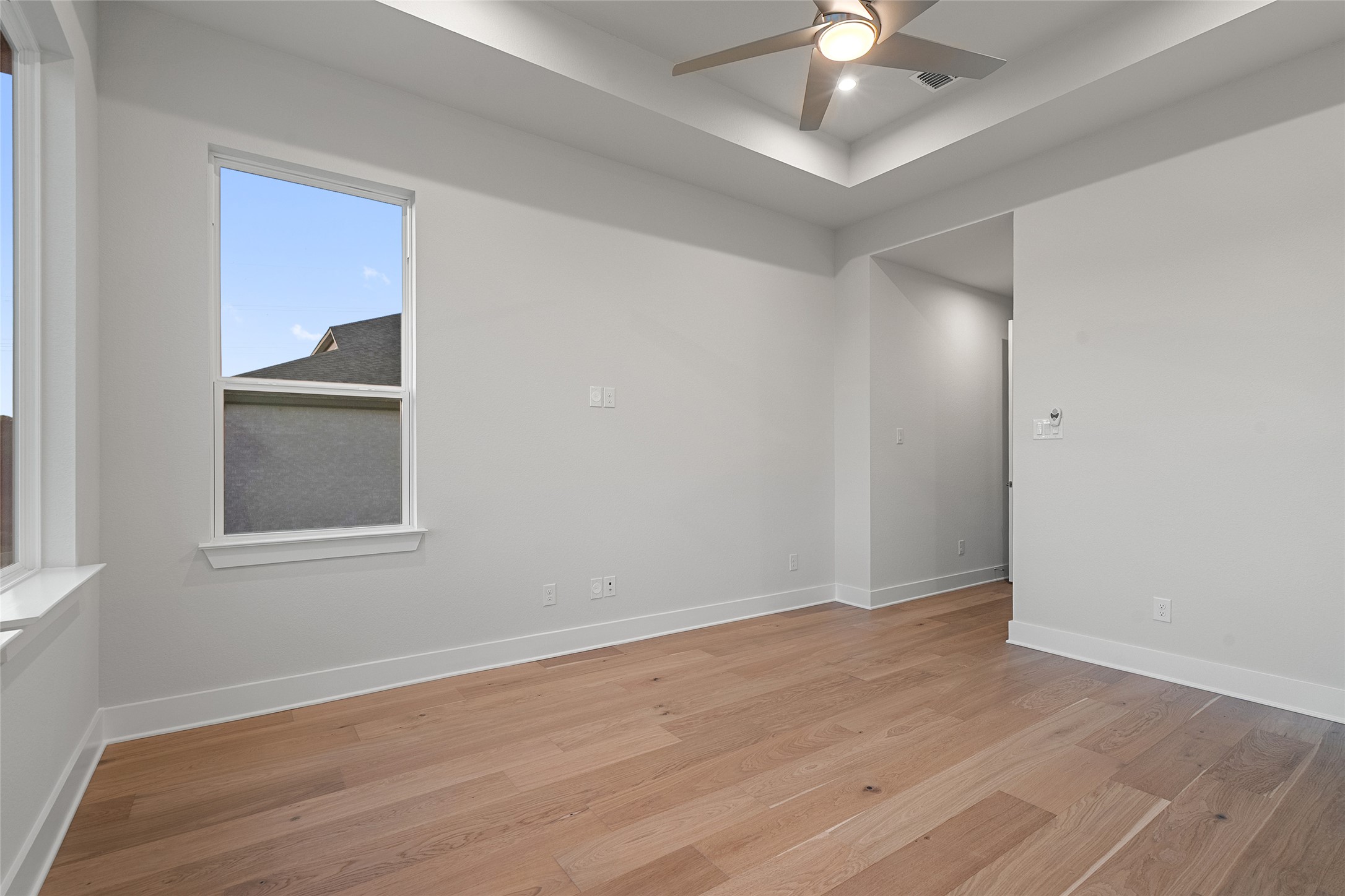 5336 Cosenza Trace Leander, TX 78641 - Photo 20 of 40 Unfurnished room featuring a raised ceiling, light wood-type flooring, and a ceiling fan