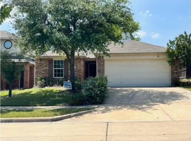 a front view of a house with garage and plants