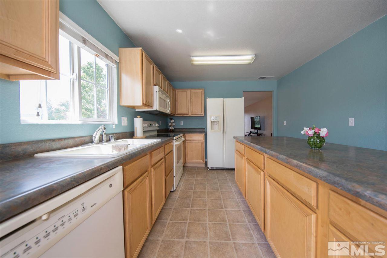 7690 Appenzell Street Reno, NV 89506 - Photo 11 of 25 a kitchen with granite countertop a sink stainless steel appliances cabinets and a window