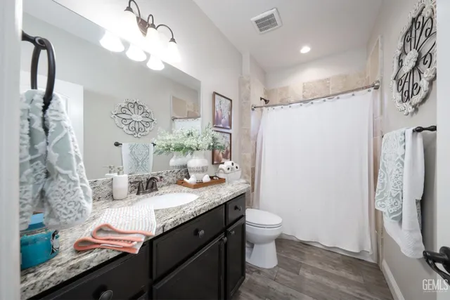 a bathroom with a granite countertop sink toilet and shower
