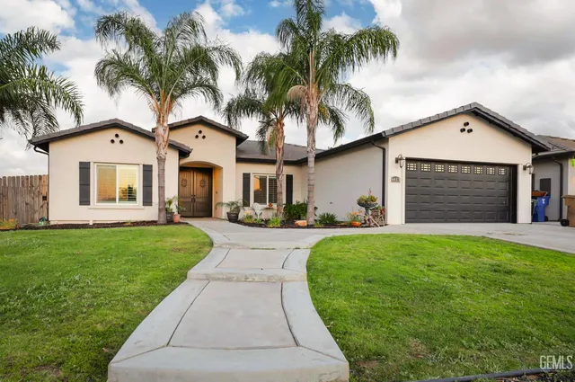 a front view of a house with a garden and palm trees