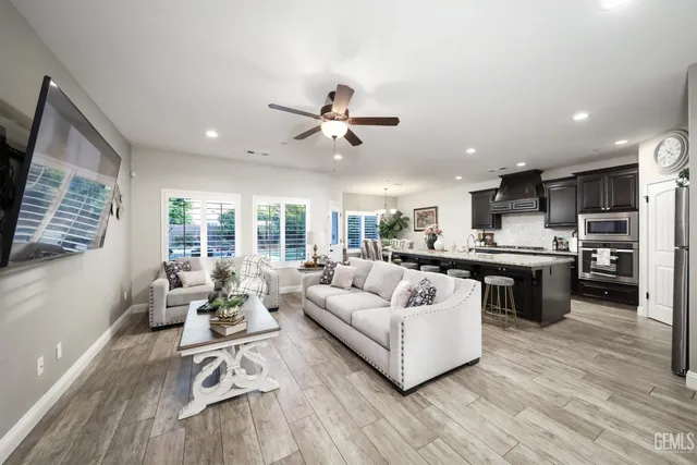 a living room with furniture kitchen area and a wooden floor
