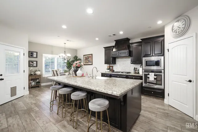 a kitchen with stainless steel appliances granite countertop a table chairs sink refrigerator and cabinets