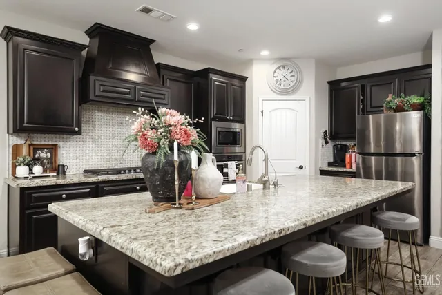 a kitchen with stainless steel appliances granite countertop a table chairs and a refrigerator
