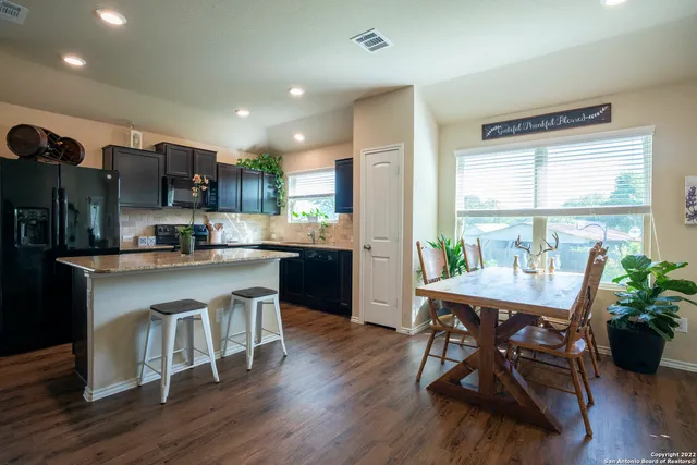 a kitchen with stainless steel appliances granite countertop a stove a refrigerator a kitchen island a stove and a wooden floors