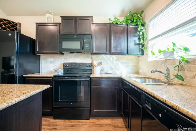 a kitchen with granite countertop a sink stove and refrigerator