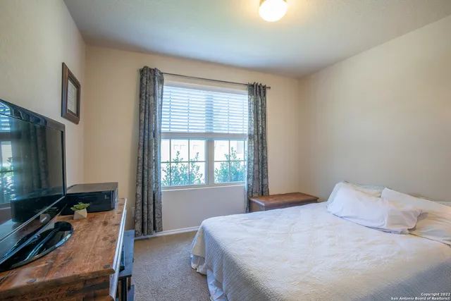 a bedroom with a bed and a flat tv screen on dresser