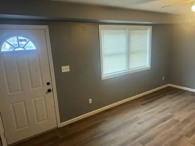 an empty room with wooden floor and windows