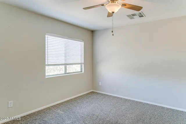 an empty room with a window and a fan