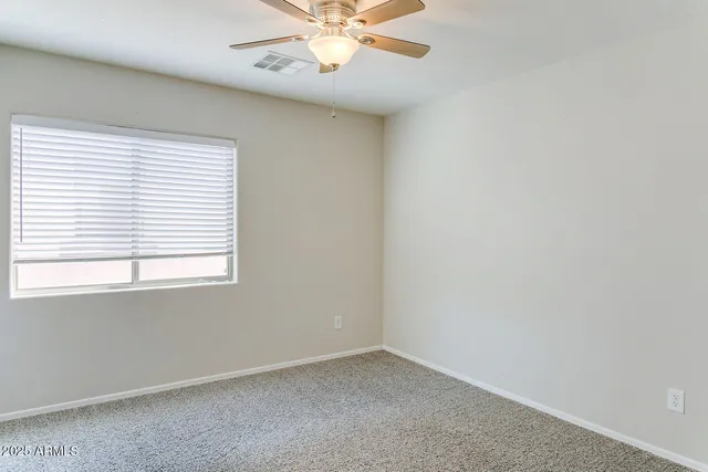 an empty room with a window and a fan
