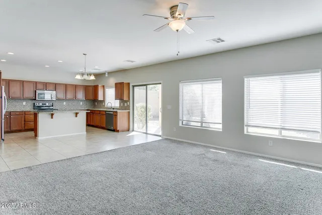 a large kitchen with stainless steel appliances granite countertop a large counter top and a chandelier