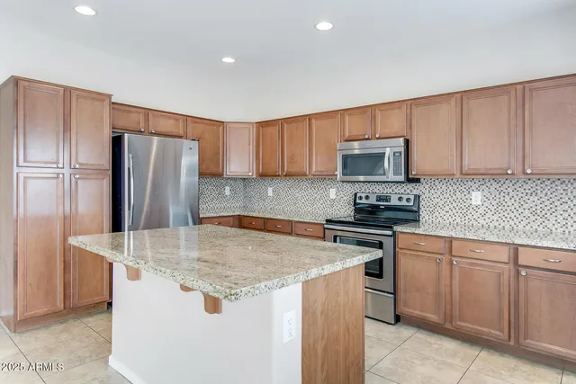 a kitchen with stainless steel appliances granite countertop a stove top oven a refrigerator and a sink