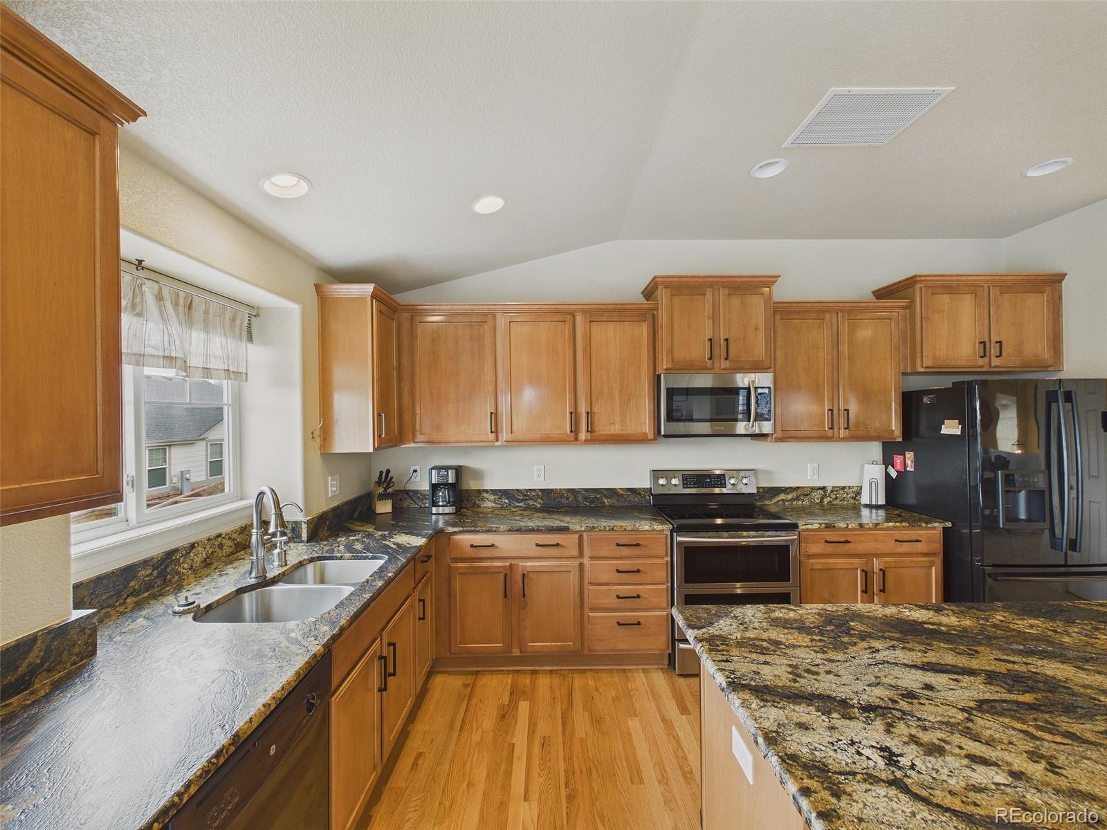 2805 South Jebel Way Aurora, CO 80013 - Photo 16 of 50 a kitchen with stainless steel appliances granite countertop a stove top oven a sink dishwasher a dining table and chairs with wooden floor