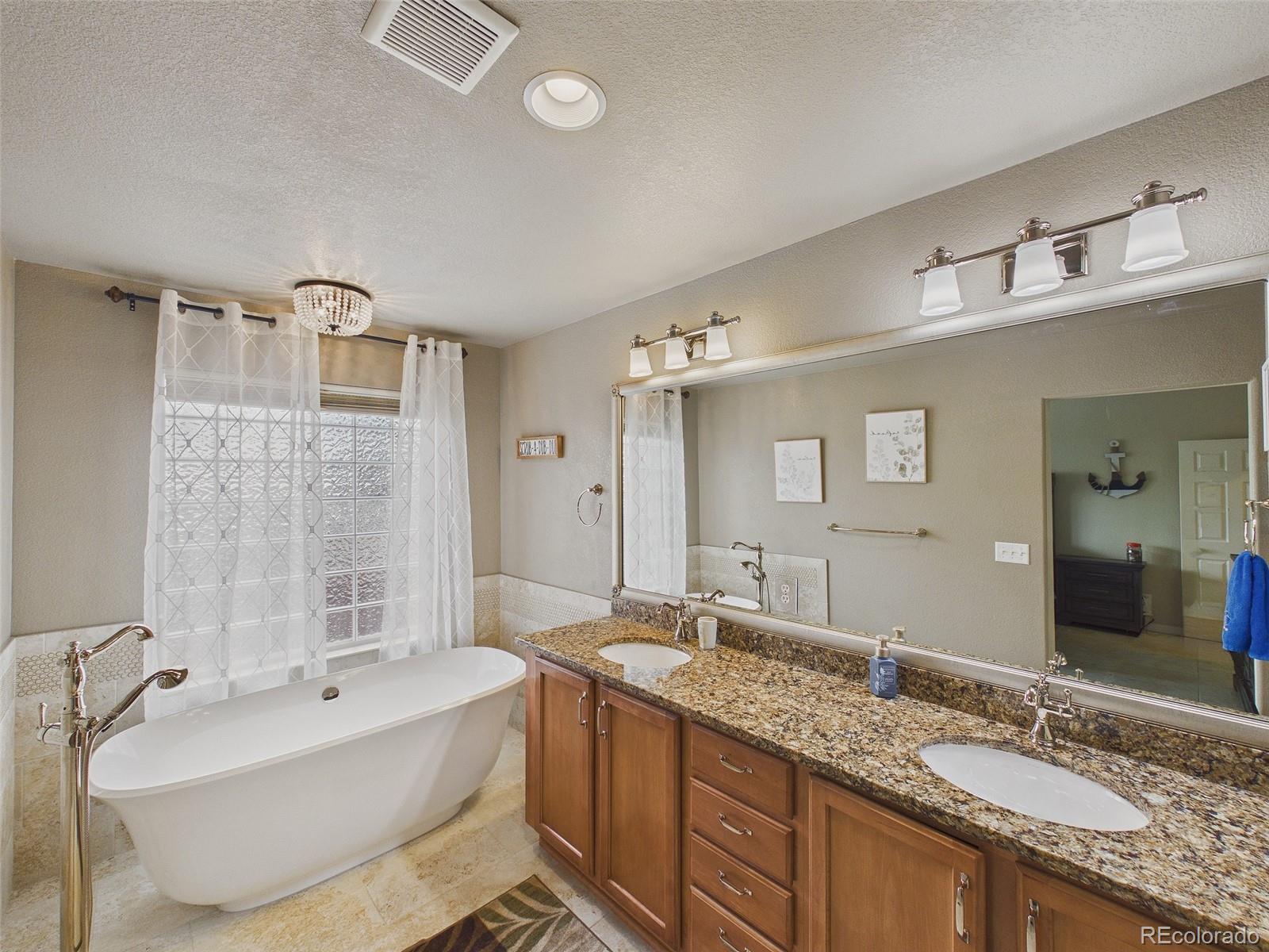 2805 South Jebel Way Aurora, CO 80013 - Photo 30 of 50 a spacious bathroom with a granite countertop tub double vanity sink and a large mirror