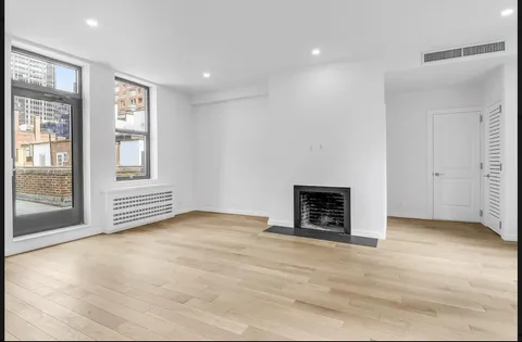 a view of an empty room with a window and fireplace