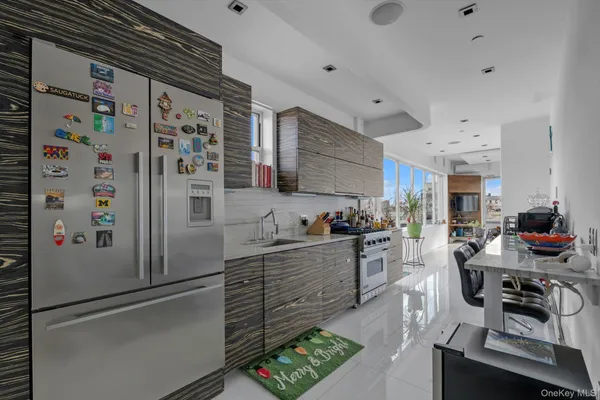 a kitchen with stainless steel appliances a refrigerator a sink a stove a dining table and chairs