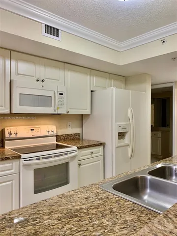 a kitchen with granite countertop a sink stove and refrigerator