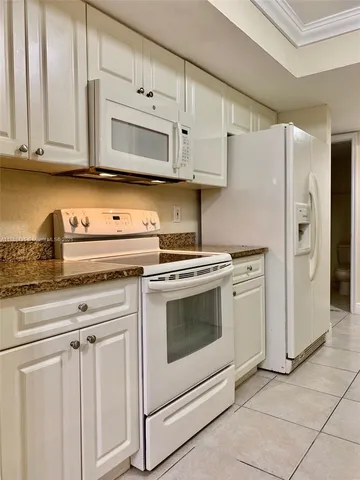 a kitchen with granite countertop white cabinets and stainless steel appliances