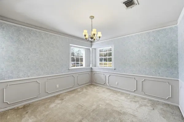 a view of an empty room with chandelier fan